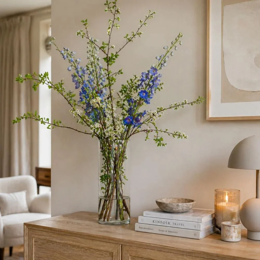 Hoge glazen vaas met bloemen en takken